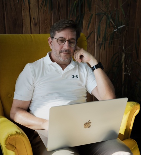 Stephen Kunstmann in einem gelben Sessel mit Laptop